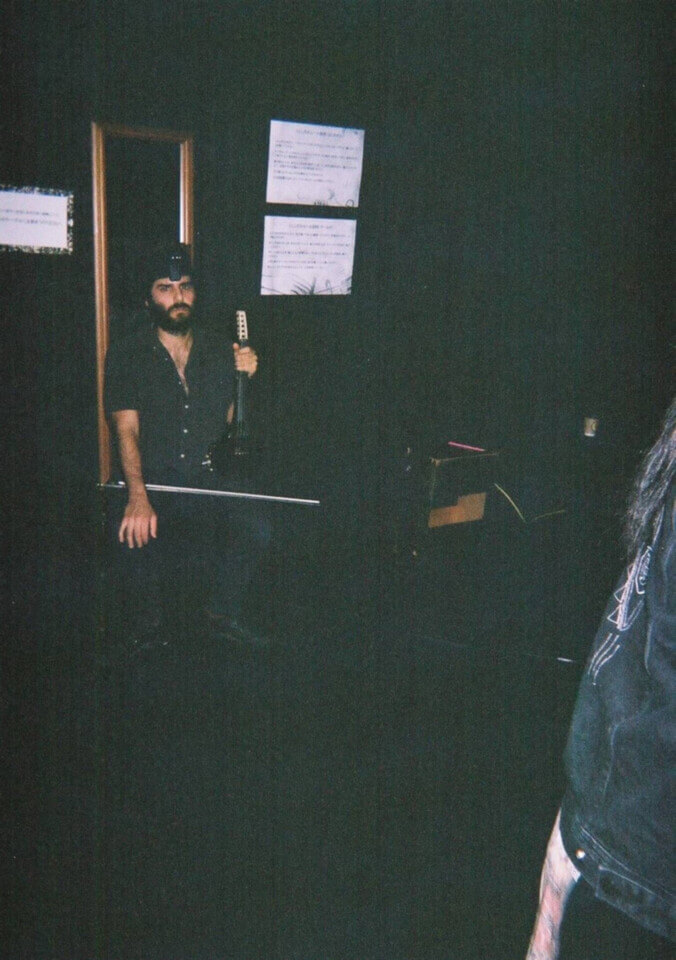 disposable camera shot showing stephan e perez sitting in front of a mirror, a webcam on his head and a midi violin on his knee.